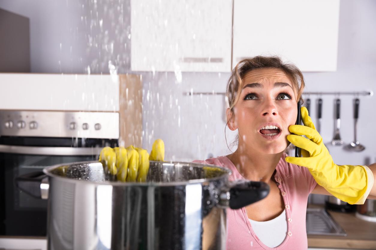 Woman calling plumber to fix water leaking from the ceiling.