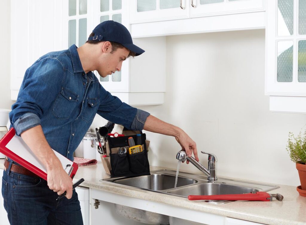 Plumber performing maintenance and inspection on kitchen faucet